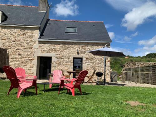 a group of chairs and an umbrella in front of a building at Les écuries du Nevez in Plonéour-Lanvern