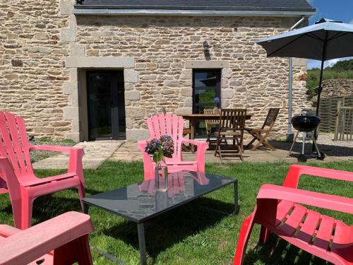 a group of pink chairs and a table in a yard at Les écuries du Nevez in Plonéour-Lanvern