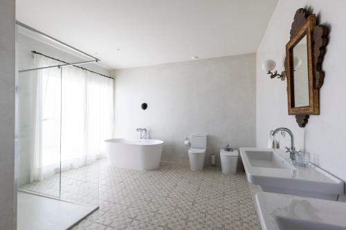 a bathroom with two toilets and a tub and a sink at Casa Pizarro Hotel in Cáceres