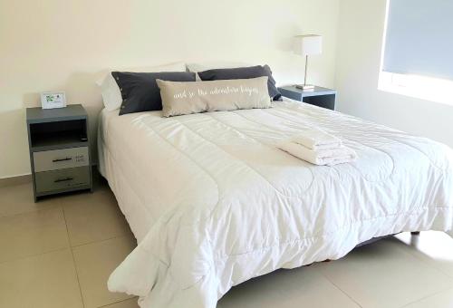 uma cama branca com duas toalhas em cima em House Rental RG_Departamento#1 em Rio Grande