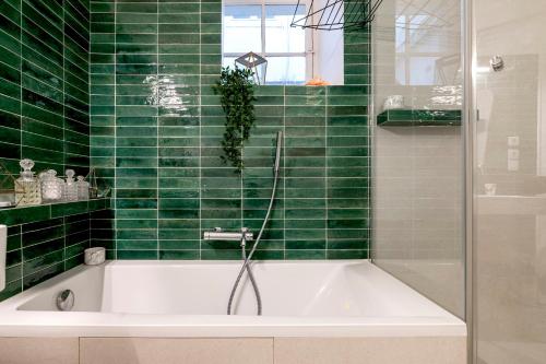 a green tiled bathroom with a white bath tub at Veeve - The Hopeful Romantic in Paris