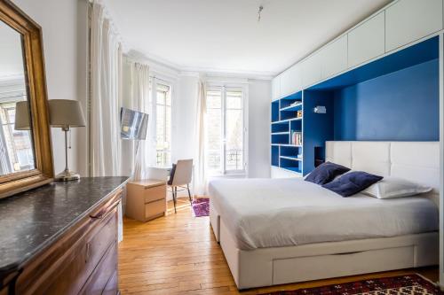 une chambre avec un grand lit avec une tête de lit bleue dans l'établissement Veeve - Dreaming in the Daytime, à Paris