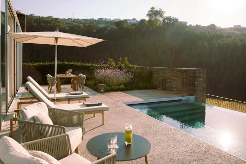a patio with chairs and an umbrella and a pool at Octant Douro in Castelo de Paiva