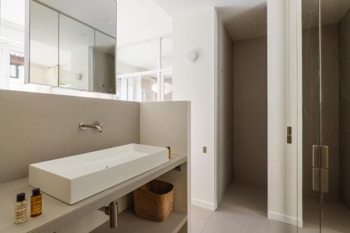 une salle de bain avec un lavabo blanc et un miroir dans l'établissement Veeve - Alabaster Bright, à Paris