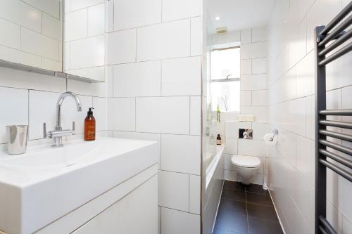 a white bathroom with a sink and a toilet at Veeve - Explorer's Escape in London