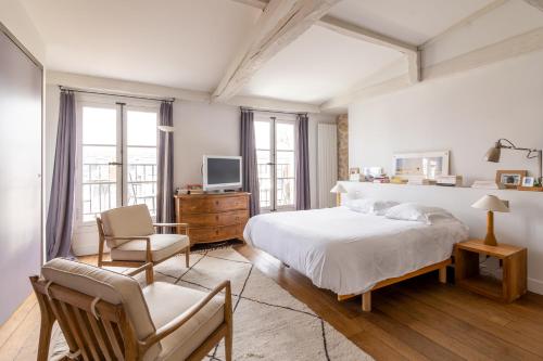 a bedroom with a bed and a tv and a chair at Veeve - Loft Living on Luxembourg in Paris