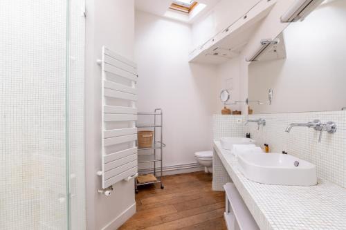 a white bathroom with a sink and a toilet at Veeve - Loft Living on Luxembourg in Paris