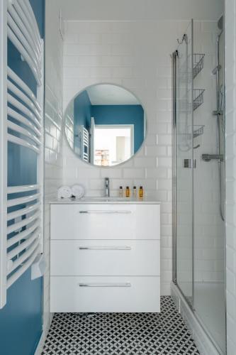 une salle de bain blanche avec un lavabo et un miroir dans l'établissement Veeve - A Kiss of Blue, à Paris