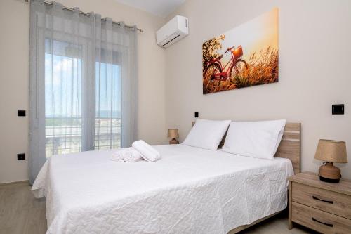 a bedroom with a white bed and a large window at Alexandra's comfort by homebrain in Alexandroupoli