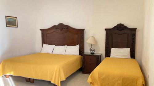 two beds in a hotel room with yellow sheets at Mansion Serrano Hotel in El Fuerte
