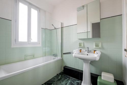 une salle de bain blanche avec un lavabo et une baignoire dans l'établissement Veeve - Montmartre Majestique, à Paris