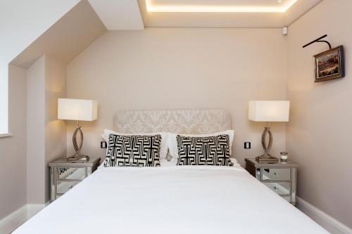 ein Schlafzimmer mit einem großen weißen Bett mit zwei Lampen in der Unterkunft Veeve - Lavish and Luxe in London