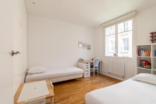 um quarto com 2 camas, uma secretária e uma janela em Veeve - Ethereal Light em Paris