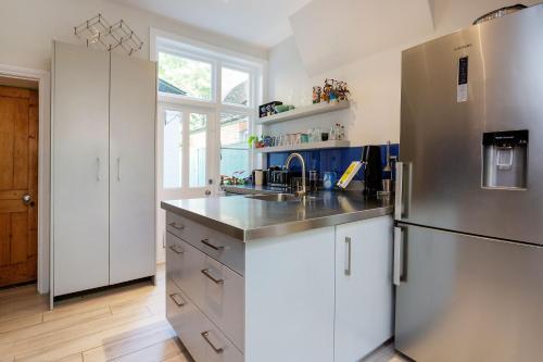 a kitchen with white cabinets and a stainless steel refrigerator at Veeve - Parkland Perfection in London