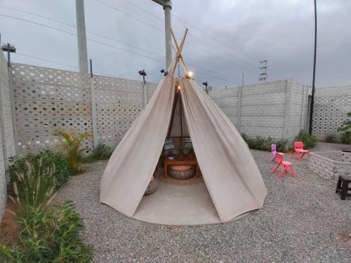 a teepee tent in a garden with two pink chairs at Desert Lodges - La Terracota in Ica