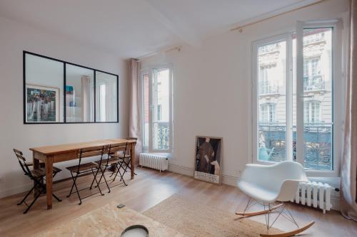 une salle à manger avec une table, des chaises et des fenêtres dans l'établissement Veeve - White Beauty, à Paris