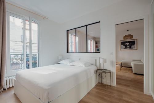 une chambre blanche avec un lit et une grande fenêtre dans l'établissement Veeve - White Beauty, à Paris