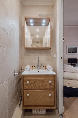 une salle de bain avec un lavabo, un miroir et un lit dans l'établissement Veeve - Gilded Dreams, à Paris