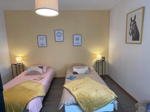 Dos camas individuales en una habitación con un caballo en la pared. en Le petit coin des oliviers, en Colmar