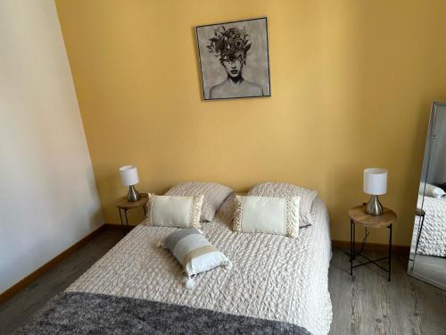 une chambre avec un lit avec des draps blancs et des oreillers dans l'établissement Le petit coin des oliviers, à Colmar