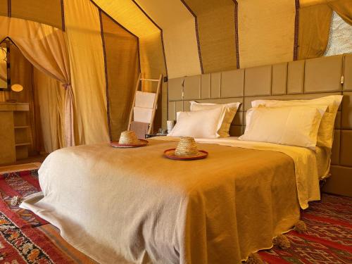 a bedroom with a bed with two hats on it at Arena Desert Camp & Activitys in Merzouga