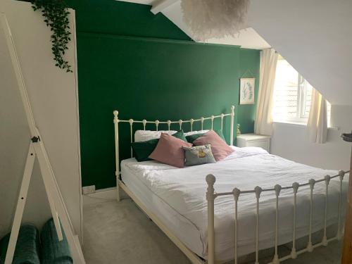 - une chambre dotée d'un mur vert et d'un lit avec des oreillers dans l'établissement Trendy Westbourne Flat, à Bournemouth