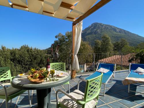 un patio con una mesa y sillas con una montaña en el fondo en Taddore Green Lodge en Galtellì
