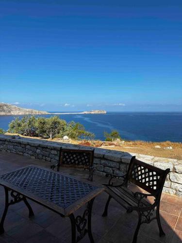 a bench sitting on top of a stone wall with the ocean at Cliffside Cozy Villa w/ Seaviews in Mézapos