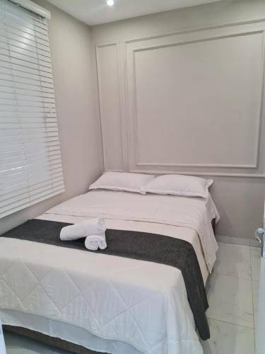 a white bedroom with a bed with a towel on it at Pousada Calma in Maputo