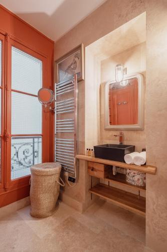 une salle de bain avec un lavabo, un miroir et une fenêtre dans l'établissement Veeve - Mid-century Mystique, à Paris