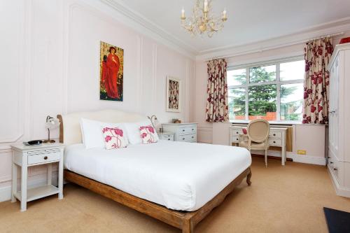 um quarto com uma grande cama branca e uma secretária em Veeve - Courtside Dreams em Londres