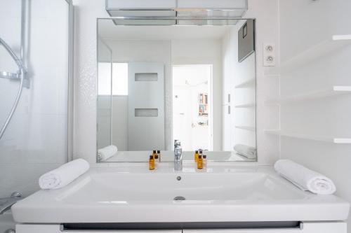 une salle de bain blanche avec un lavabo et un miroir dans l'établissement Veeve - Spirit of Saint-Georges, à Paris