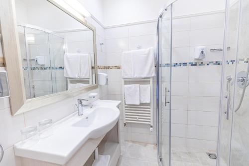 a white bathroom with a sink and a shower at City Hotel Miskolc in Miskolc