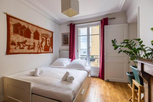 une chambre avec un lit et une grande fenêtre dans l'établissement Veeve - A la mode in Batignolles, à Paris