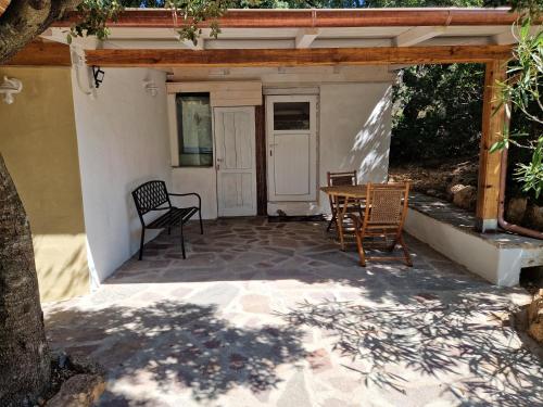 a patio with two chairs and a table and a door at Exotic sleeping in the woods near Olbia in Telti