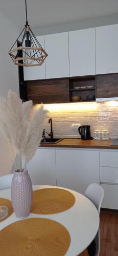 a white kitchen with a table and a vase with flowers at Planinska idila in Kopaonik