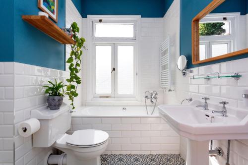 a bathroom with a toilet and a tub and a sink at Veeve - Blissful Oasis in London