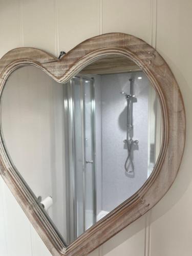 un espejo en la forma de un corazón en una pared en The Pod & Cwtch luxury accommodation en Aberaeron