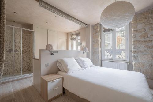 een slaapkamer met een wit bed en een stenen muur bij Veeve - Artistic Flamboyance in Boulogne-Billancourt