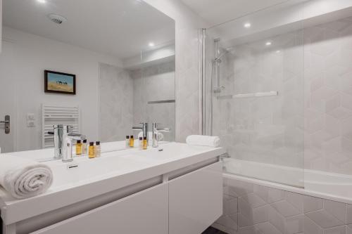 une salle de bain blanche avec un lavabo et une douche dans l'établissement Veeve - Eyes Towards the Eiffel, à Boulogne-Billancourt
