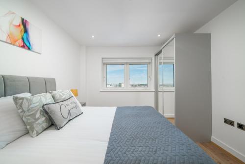 a white bedroom with a large bed and windows at Skyvillion - London River Thames Top Floor Apartments by Woolwich Ferry, Mins to London ExCel, O2 Arena , London City Airport with Parking in London