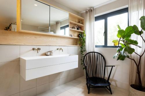 a bathroom with a sink and a chair and a mirror at Veeve - Visual Virtuosity in London