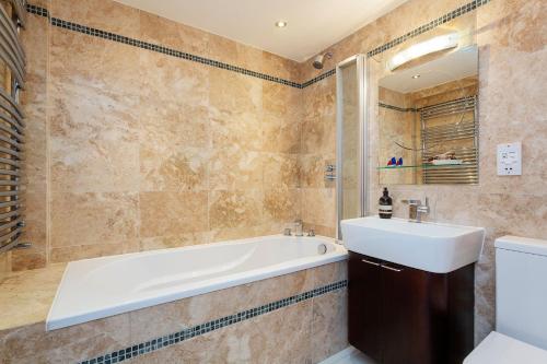 a bathroom with a tub and a sink and a toilet at Veeve - Canalside Comfort in London