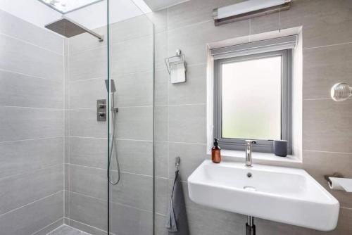 een witte badkamer met een wastafel en een douche bij The Helvellyn in Falmouth