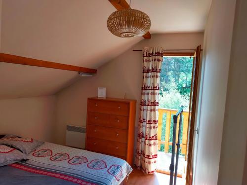 a bedroom with a bed and a sliding glass door at Maison lotissement du Bérard in Faucon-de-Barcelonnette