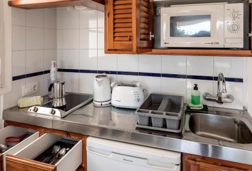 a kitchen counter with a sink and a microwave at Apartamentos Las Brisas I & II in Cala'n Bosch
