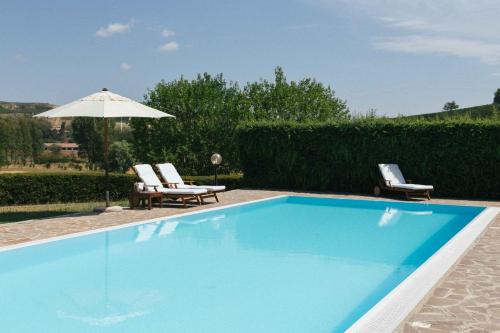 una piscina con due sedie e un ombrellone di Apart-Agriturismo "La Colomba" Nizza Monferrato a Nizza Monferrato
