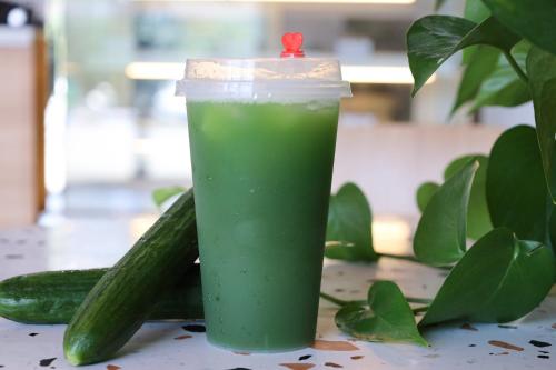 a green drink in a plastic cup next to cucumbers at Holiday Inn Fuyang by IHG in Fuyang