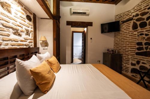 a bedroom with a bed with white pillows and a brick wall at Entre Dos Aguas Hotel Boutique in Toledo