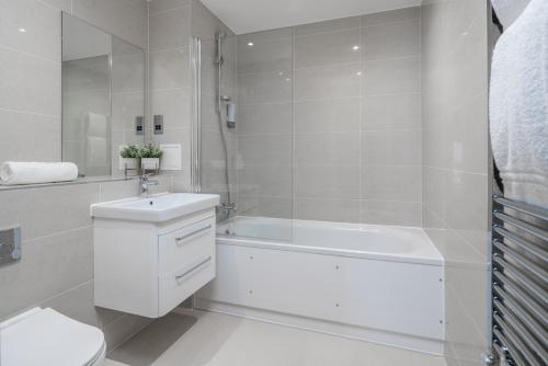 a white bathroom with a tub and a sink and a toilet at Skyvillion - London River Thames Top Floor Apartments by Woolwich Ferry, Mins to London ExCel, O2 Arena , London City Airport with Parking in London